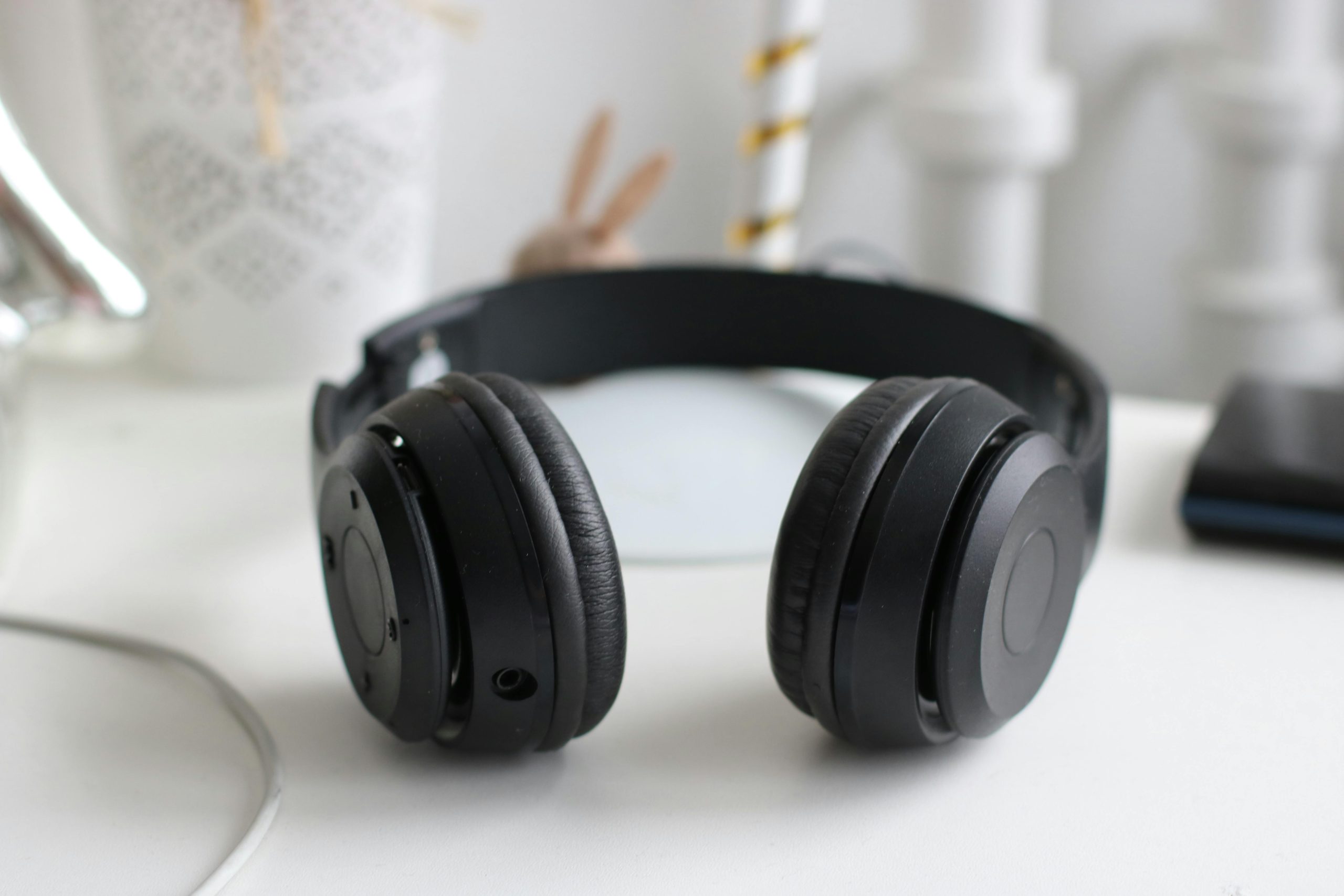 Close-up of black wireless headphones on a white desk in a modern setting.